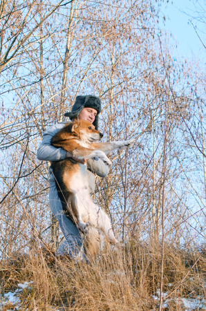 young man carries a dog through the impassable winter forestの写真素材
