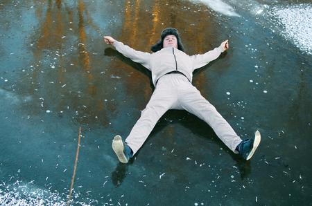 guy in the gray tracksuit lying on the ice with his arms outstretchedの写真素材