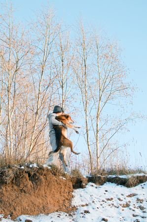 young man carries a dog through the impassable winter forestの写真素材