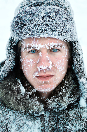 male face covered with snow with bright blue eyesの写真素材