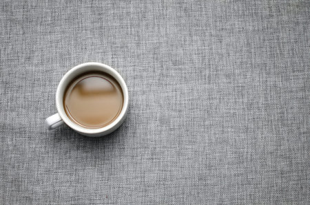 Cup of coffee on grey fabric surface close-up-background image