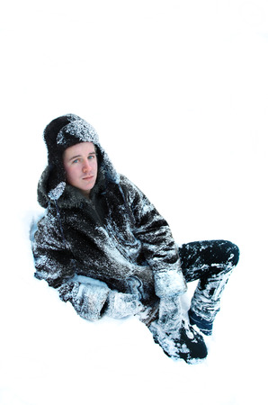 portrait of a young man in a snow-covered coat and hatの写真素材