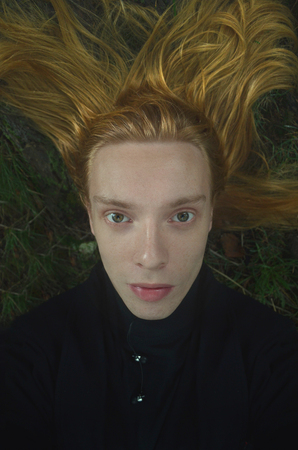 portrait of a young man with long blond hair spread out on the groundの写真素材