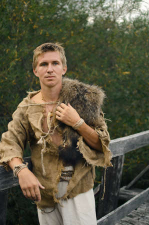 young man stripped to the waist stands in a wild field with his arms outstretchedの写真素材