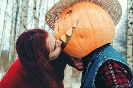 Halloween Scarecrow with a pumpkin on his head and an evil witch with a broom in her hands met in the woodsの写真素材