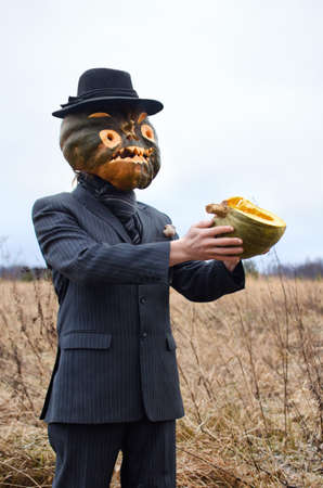 man in a fancy dress is celebrating Halloween and showing a cut up ripe pumpkinの写真素材
