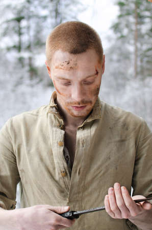 young soldier in a world war II uniform is sitting in a winter forest looking upの写真素材