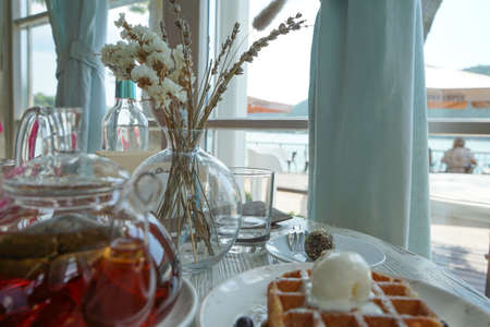 a pleasant atmosphere of summer cafes in parks on the shore of the mountain lake abrau-dyurso. Delicious Belgian waffle with ice cream, blueberries and hot tea.の写真素材