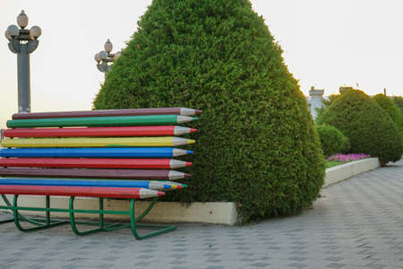 beautiful bench in a city park with beautiful trees, flowers, shrubs and street lights on a summer dayの写真素材