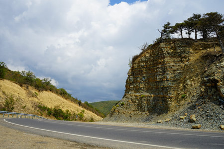 winding road with markings in the mountains against the background of beautiful white clouds in the...