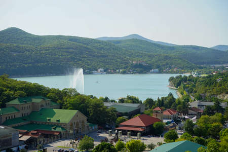 a beautiful view of the mountain lake Abrau Dyurso with a high-spouting fountain and mountains overgrown with dense green vegetation on a warm summer dayのeditorial素材