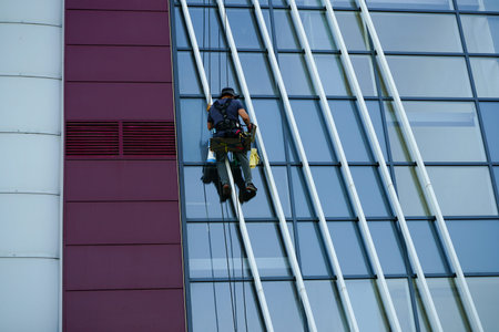 Novorossiysk, Krasnodar Territory / Russia - 09.17.2020: A high-altitude worker washes the windows...