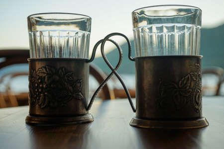 two glass glasses in vintage cup holders close up on the tableの写真素材