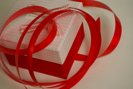 a beautiful red gift box tied with a bright red ribbon lies on the bedside table