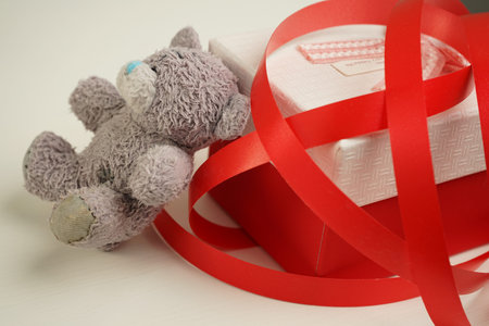 vintage teddy bear sitting on the bedside table next to a gift box tied with bright red ribbon