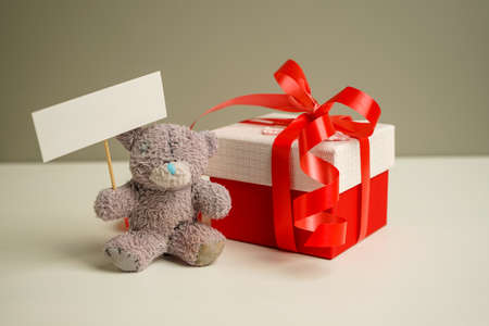 vintage teddy bear sits on the bedside table next to a gift box and holds a sign in its paws with copy spaceの写真素材