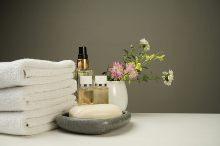 a shower set on the bedside table, clean white terry towels, several bottles of shower gel and...