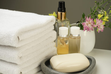 a shower set on the bedside table, clean white terry towels, several bottles of shower gel and...