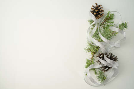 Christmas composition of coniferous tree branches, pine cones and silver ribbon next to the white Copy spaceの写真素材