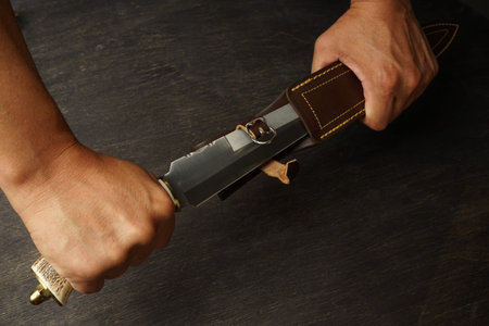the man is holding a large double-edged knife with a bone handle, pulling it out of its scabbard