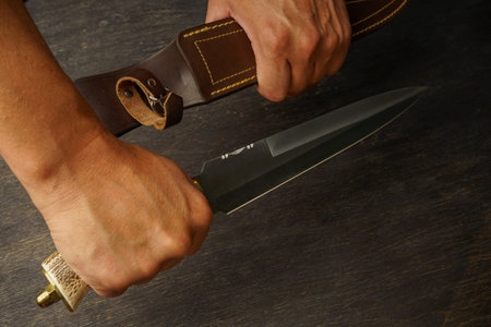 the man holds a large double-edged knife with a bone handle, having taken it out of the scabbard