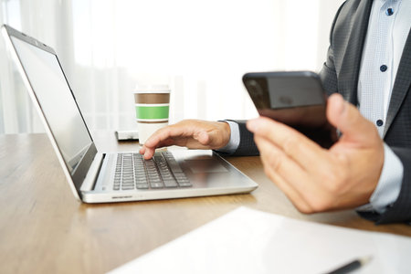 male businessman makes online purchases using laptop and smartphone