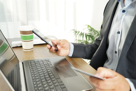 male businessman makes online purchases using a credit card, laptop and smartphone