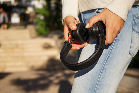 a woman in a white knitted sweater and jeans with headphones during a walk in the autumn Park