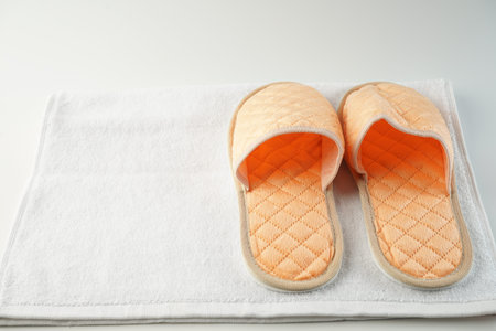 clean hotel disposable peach colored Slippers stand on a clean white Terry towel