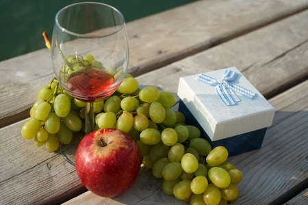 fruit and gift box on the pier and a glass of wineの写真素材