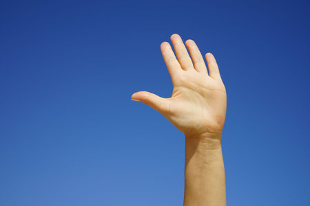 female hand close-up against a cloudless blue sky