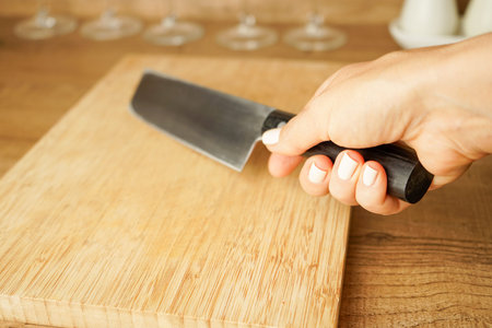 a woman's hand holds a kitchen knife for slicing vegetables