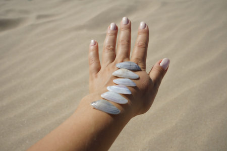 hand Spa treatment with seashells on the background of sea sand