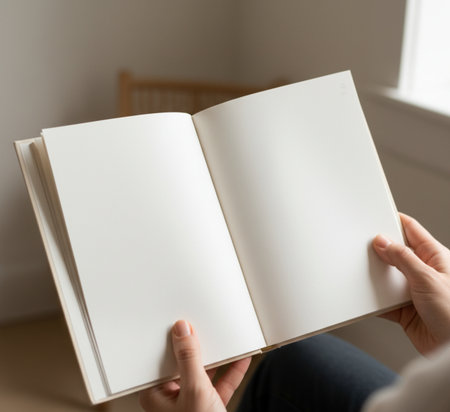 Woman's hands holding a book in front of a window, close upの素材