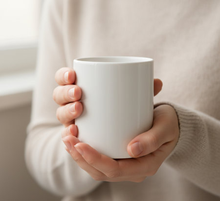Woman holding cup of coffee at home, closeup. Cozy atmosphereの素材