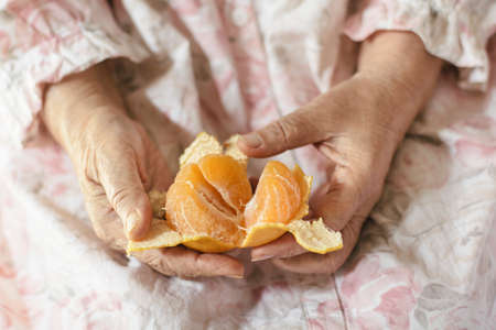 Old woman s hand is peeling a chinese orangeの写真素材