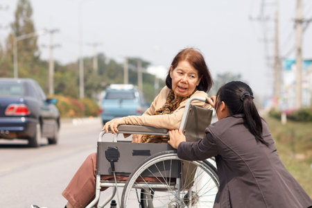 senior woman using a wheelchair to cross streetの写真素材