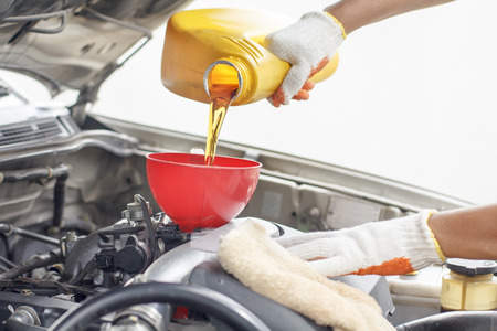 Car mechanic pouring new oil to engine.の写真素材