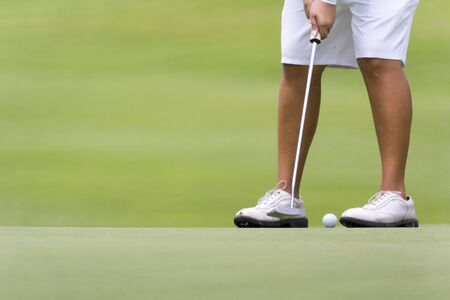 Female golfer putting on green.の写真素材