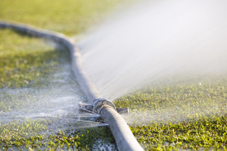 wasting water - water leaking from hole in a hoseの写真素材