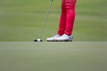 Female golfer putting, selective focus on golf ballの写真素材
