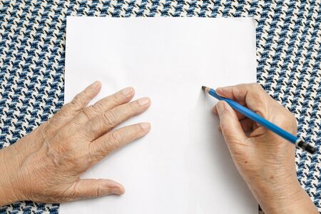 elderly woman writing on blank paper.の写真素材