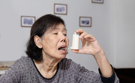 Elderly woman choking and holding an asthma sprayの写真素材