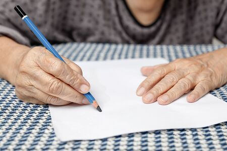 elderly woman writing on blank paperの写真素材