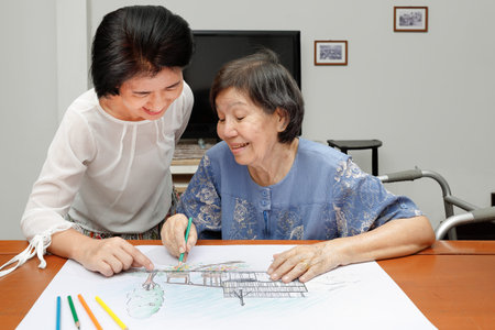 Elderly woman painting color on her drawing with daughter , hobby at home