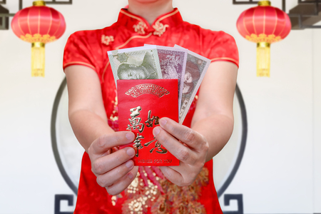 chinese woman holding new year red envelope or hong bao , text mean best whishes for you.の写真素材