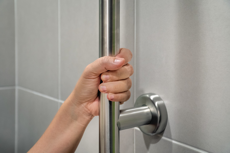 woman holding handrail in toilet.の写真素材