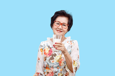 Senior woman holding a glass of milk , isolated on white background.の写真素材