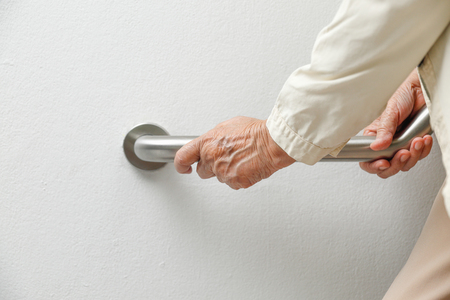 Elderly woman holding on handrail for safety walk stepsの写真素材