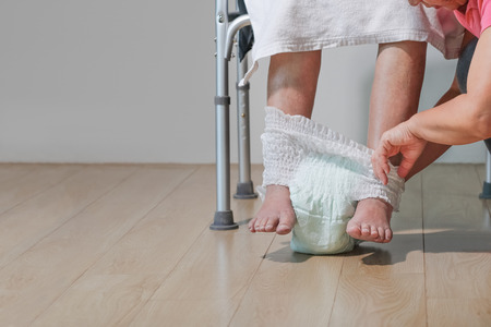 elderly woman changing diaper with caregiverの写真素材